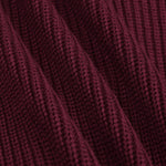 Close-up of a ribbed knit fabric in a deep burgundy or maroon color, showing the detailed texture and folds of the material.
