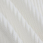 A close-up of a white textured knit fabric with a subtle diagonal ribbed pattern.