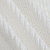 A close-up of a white textured knit fabric with a subtle diagonal ribbed pattern.