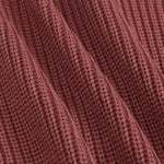 Close-up of a ribbed knit fabric in a dusty rose or mauve color, showing the detailed texture and folds of the material.