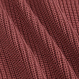 Close-up of a ribbed knit fabric in a dusty rose or mauve color, showing the detailed texture and folds of the material.