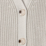 Close-up of a cream-colored ribbed knit cardigan sweater showing the button placket with two light beige buttons.