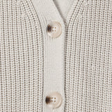 Close-up of a cream-colored ribbed knit cardigan sweater showing the button placket with two light beige buttons.