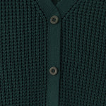 Close-up of a dark green waffle-knit cardigan sweater with a V-neck and three dark buttons.