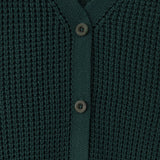 Close-up of a dark green waffle-knit cardigan sweater with a V-neck and three dark buttons.