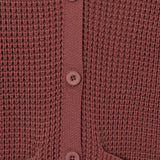 Close-up of a waffle-knit cardigan in a dusty rose or mauve color, featuring a matching button placket and ribbed collar.