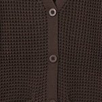 Close-up of a dark brown waffle-knit cardigan sweater showing the buttoned front and ribbed collar, cuffs, and hem.