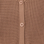 Close-up of a brown waffle-knit cardigan sweater showing the button-up front with matching buttons and ribbed trim.