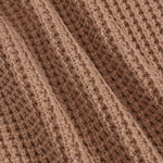 Close-up of a brown ribbed knit fabric texture with a waffle-like pattern.