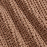 Close-up of a brown ribbed knit fabric texture with a waffle-like pattern.