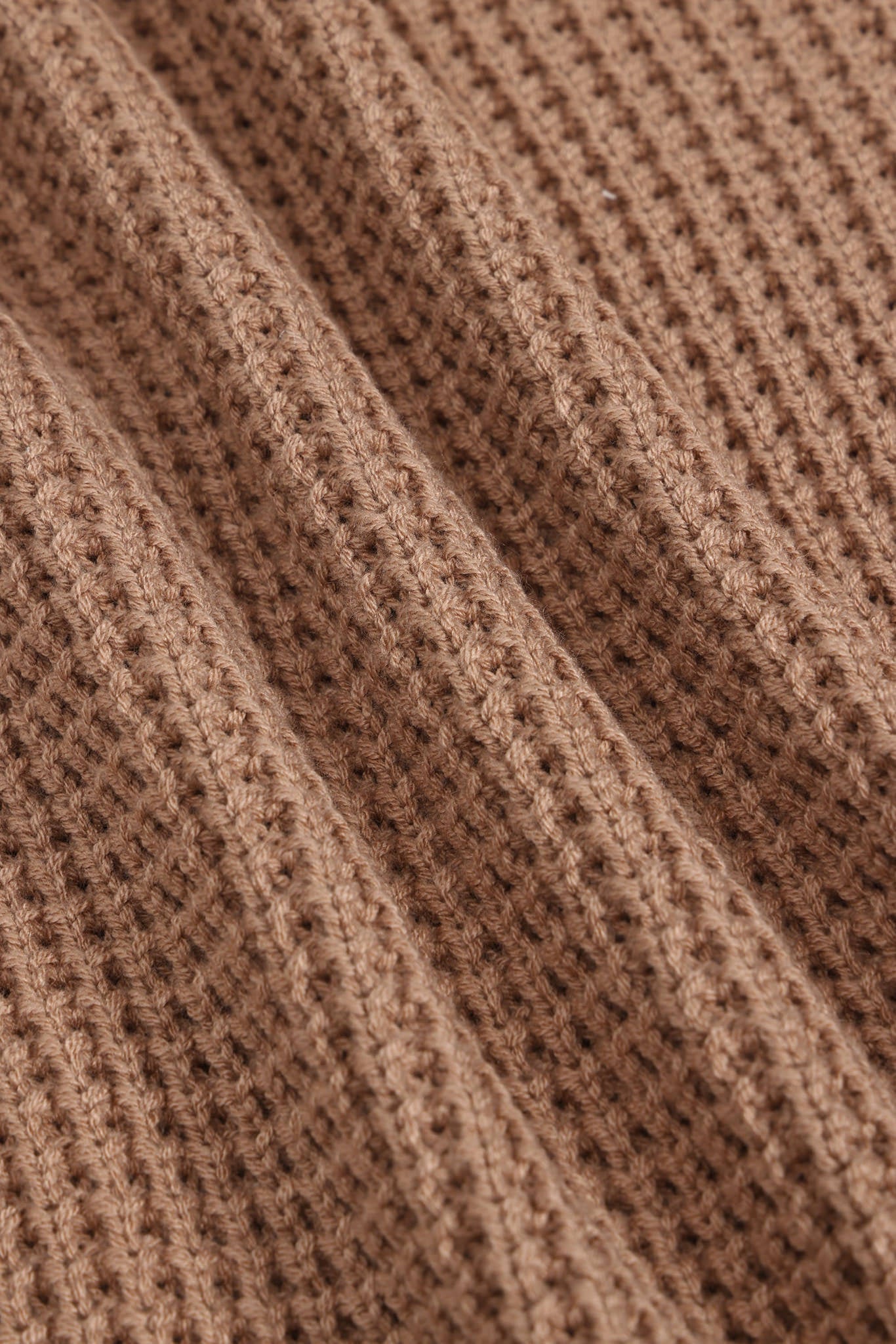 Close-up of a brown ribbed knit fabric texture with a waffle-like pattern.