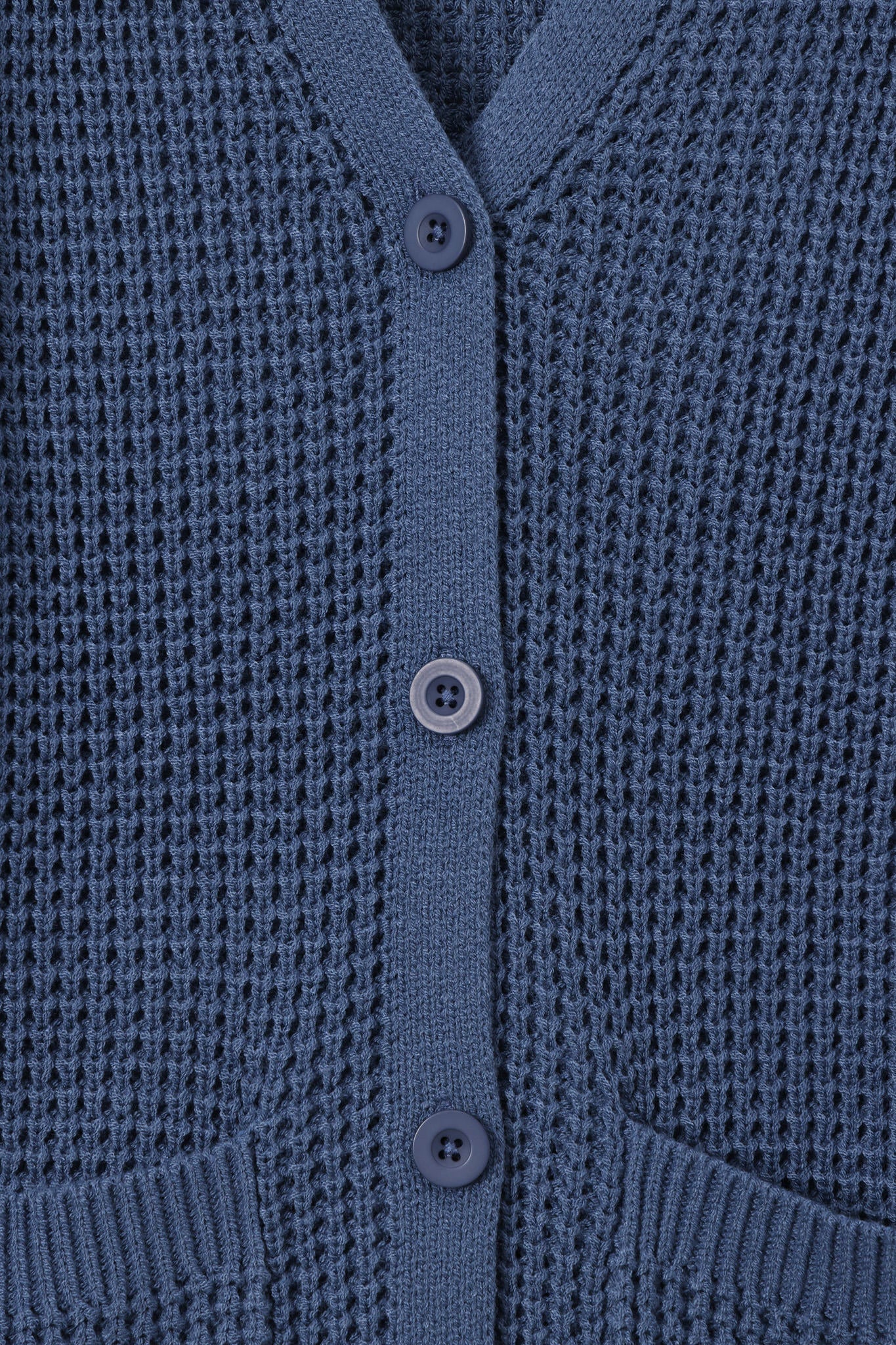 Close-up of a textured knit cardigan in a muted slate blue color, featuring a buttoned front closure and ribbed trim.
