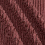 Close-up of a ribbed knit fabric in a dusty rose or mauve-brown color, showing the detailed texture and folds of the yarn.