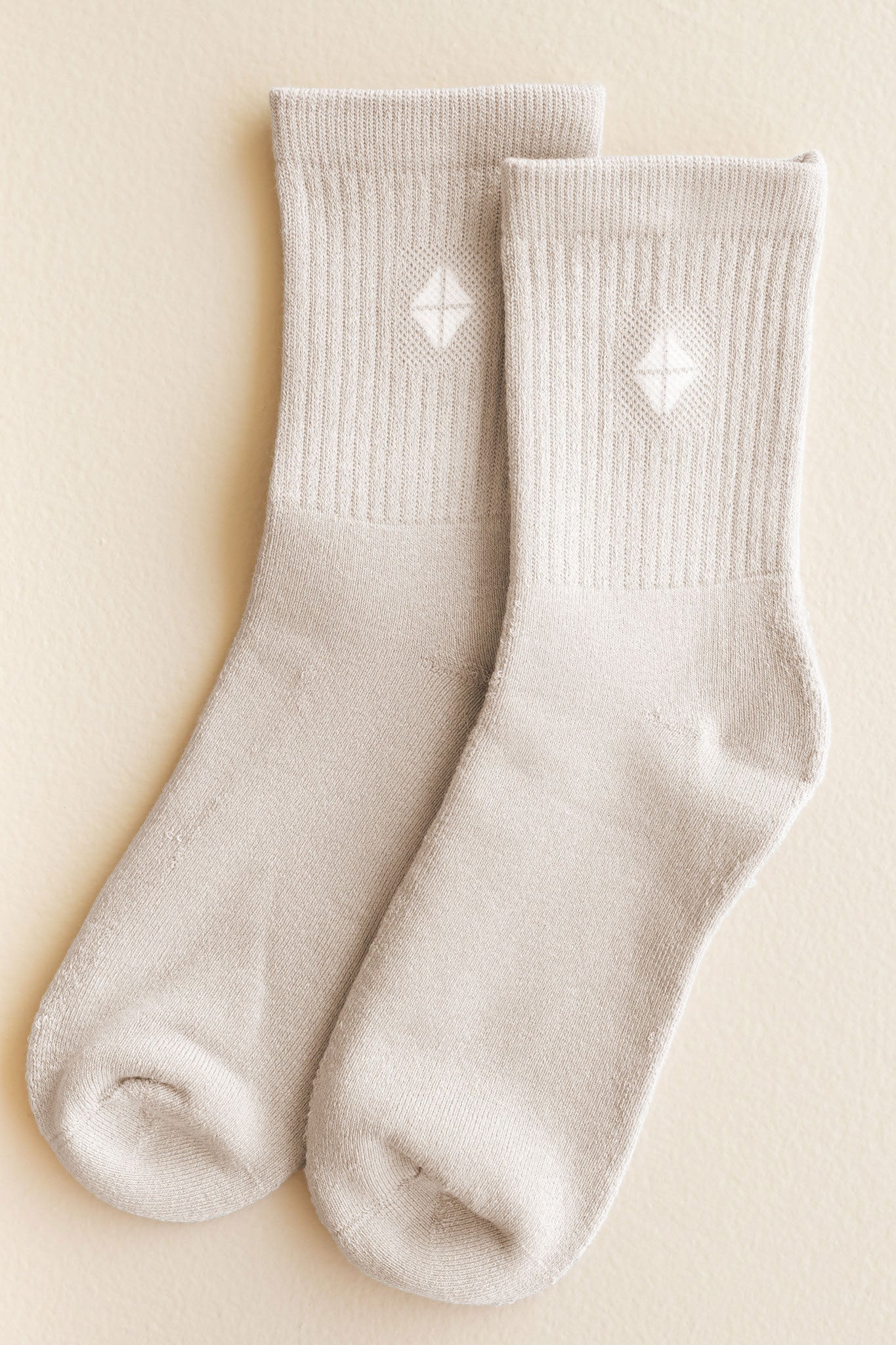 Pair of beige socks with kite pattern on a beige background