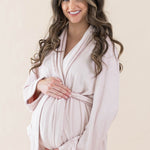 Expectant mother cradling her baby bump wearing the Adult Robe in Blush