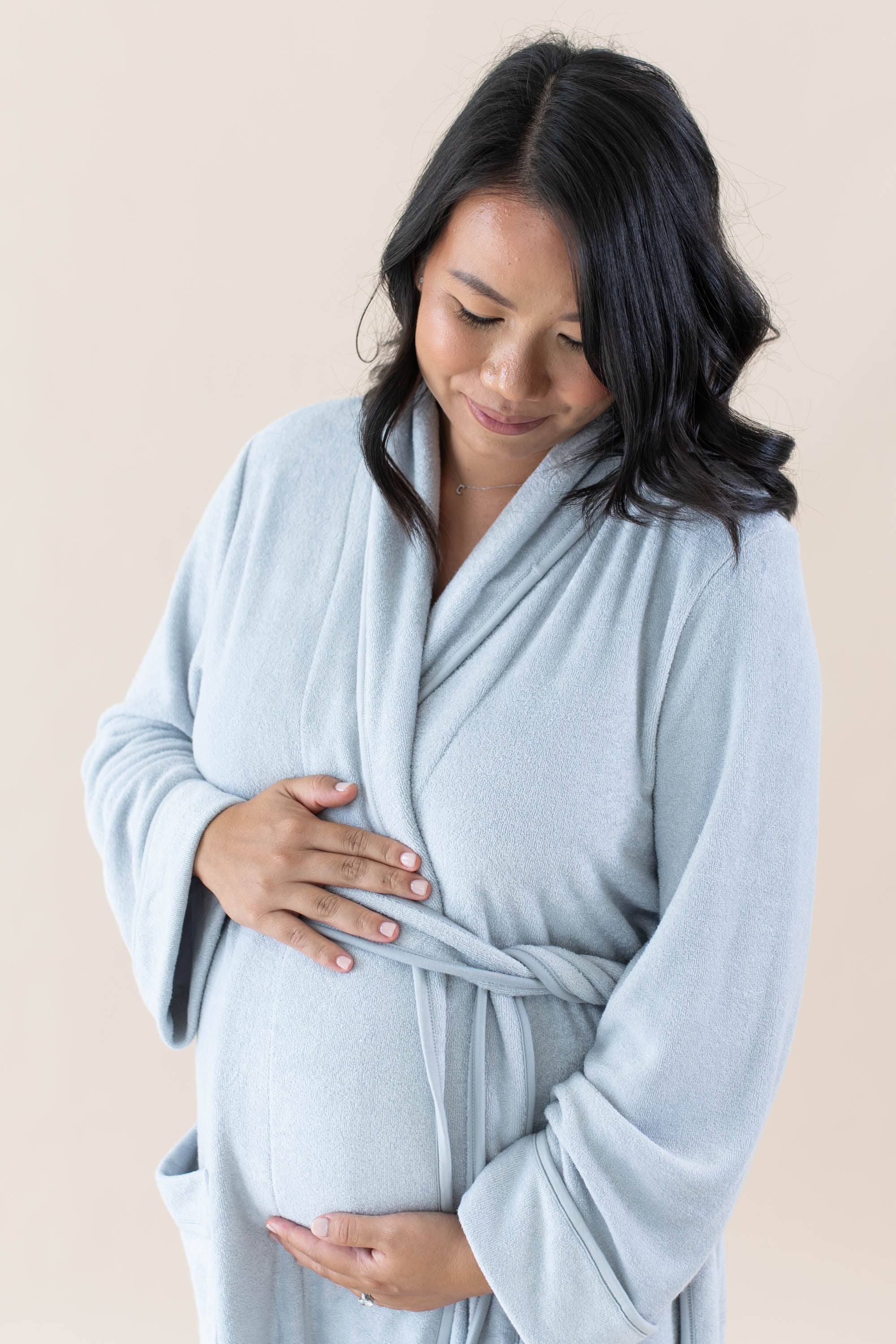 Expectant mother cradling her baby bump while wearing the Adult Robe in Storm