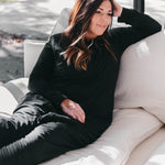 Female model sitting on a couch wearing the Adult Sleep Bag Walker in Midnight