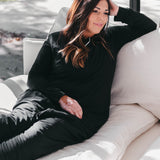 Female model sitting on a couch wearing the Adult Sleep Bag Walker in Midnight