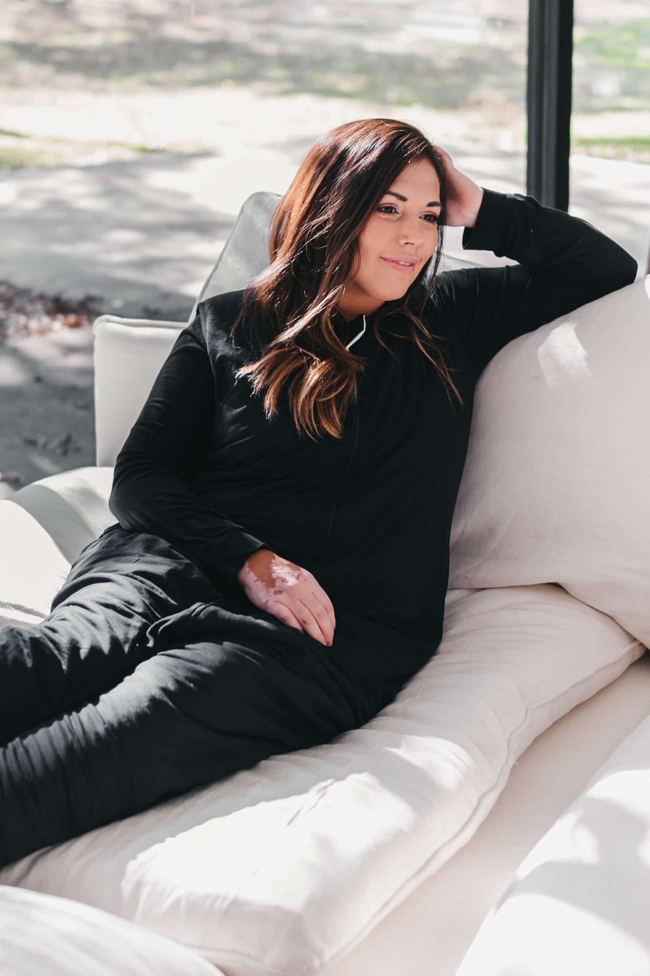 Female model sitting on a couch wearing the Adult Sleep Bag Walker in Midnight