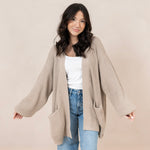 Woman modeling tan colored knit oversized cardigan with white tank and jeans