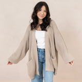 Woman modeling tan colored knit oversized cardigan with white tank and jeans