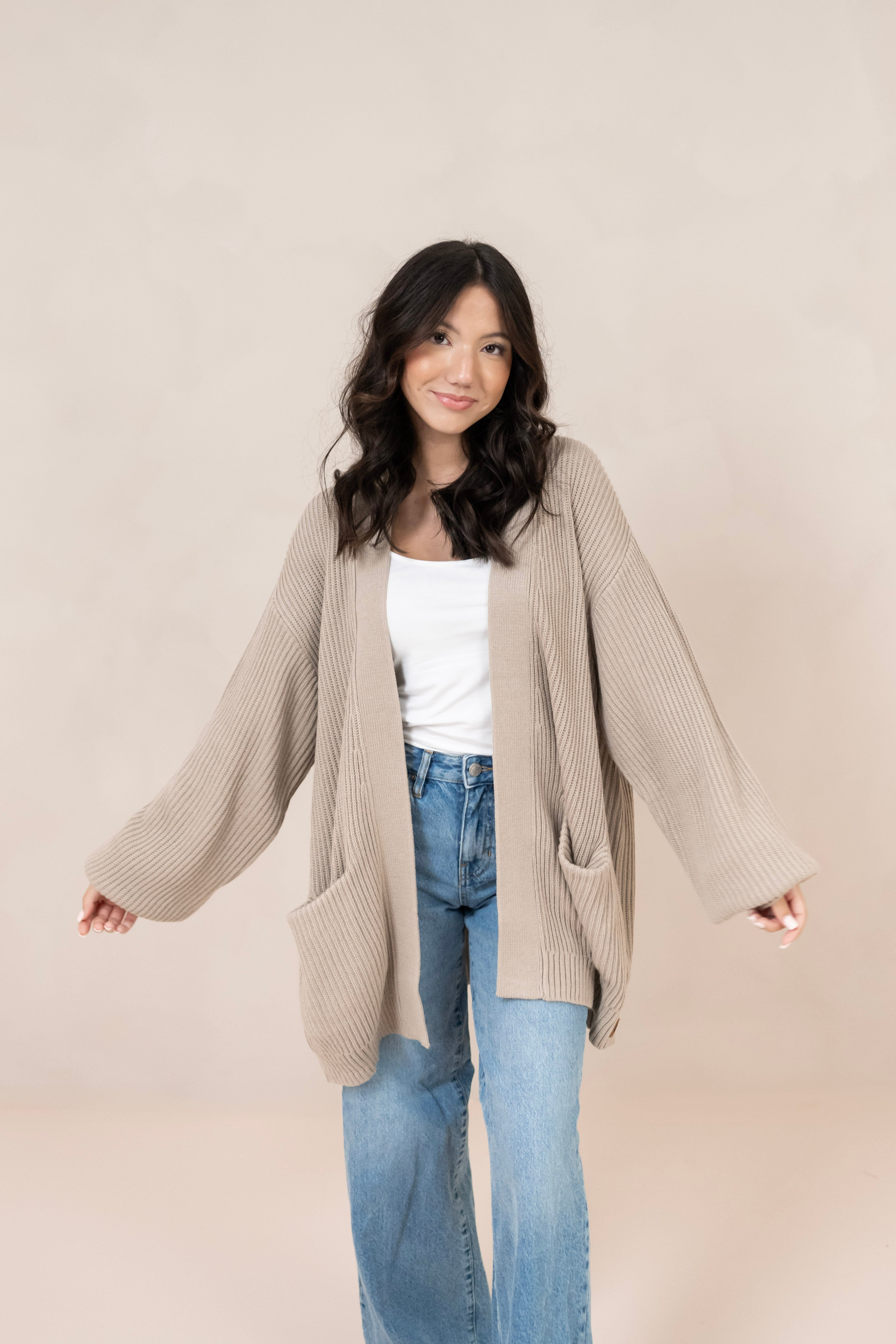 Woman modeling tan colored knit oversized cardigan with white tank and jeans
