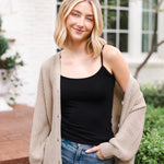 Modal posing outdoors wearing Chunky Knit Women's Waffle Cardigan in Almond over midnight camisole and blue jeans