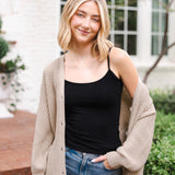 Modal posing outdoors wearing Chunky Knit Women's Waffle Cardigan in Almond over midnight camisole and blue jeans