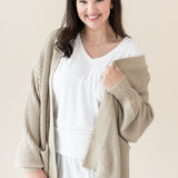Woman in white outfit modeling Chunky Knit Women's Oversized Cardigan in Almond holidng sweater