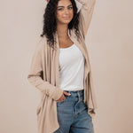 Smiling model standing with one hand in her jeans pocket with the other hand on her head wearing the Women's French Terry Wrap Top in Almond 