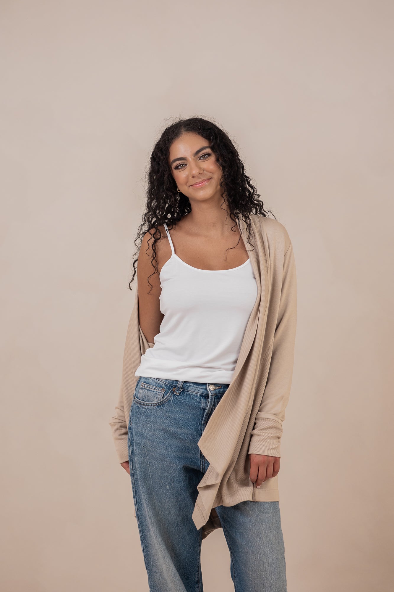 Model with the Women's French Terry Wrap Top in Almond off one shoulder paired with a Cami in Cloud and Jeans