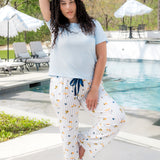 Woman posing outside of a pool with one hand over head while modeling the Women's Lounge Pants in Amalfi Coast paired with a tee in Breeze 