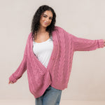 Woman with arms spread out while modeling the Kyte Cable Knite Cardigan in Apple Blossom 