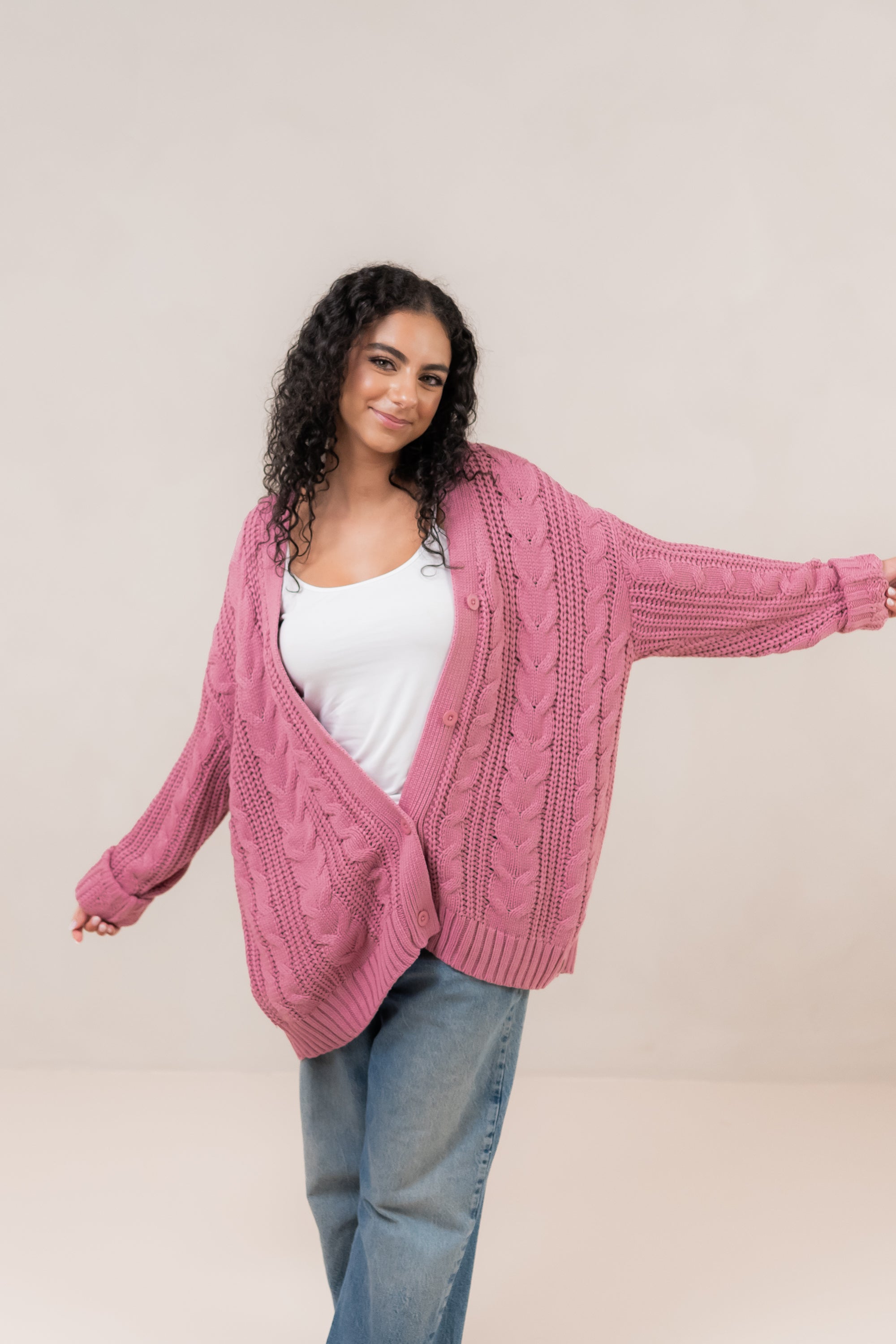 Woman with arms spread out while modeling the Kyte Cable Knite Cardigan in Apple Blossom 