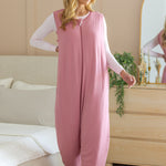 Model standing in front of a dresser and next to a bed while wearing the Adult Sleep Bag Walker in Apple Blossom
