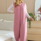 Model standing in front of a dresser and next to a bed while wearing the Adult Sleep Bag Walker in Apple Blossom