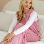 Model sitting on a bed looking to the side while wearing the Adult Sleep Bag Walker in Apple Blossom on a bed 