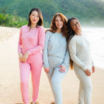 Three models standing in the sand at the beach wearing the Women's Jogger Pajama sets in various colors
