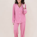 Woman smiling to the side while modeling the Kyte Women's Long Sleeve Pajama Set in Apple  Blossom with Cloud Trim