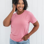 Model smiling to the side with one hand in hair while wearing the Kyte Crew Neck Tee in Apple Blossom 