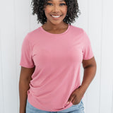 Smiling woman modeling the Kyte Crew Neck Tee in Apple Blossom paired with light blue jeans