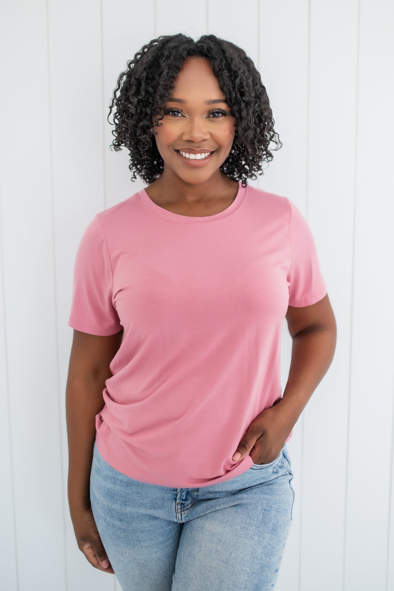 Smiling woman modeling the Kyte Crew Neck Tee in Apple Blossom paired with light blue jeans