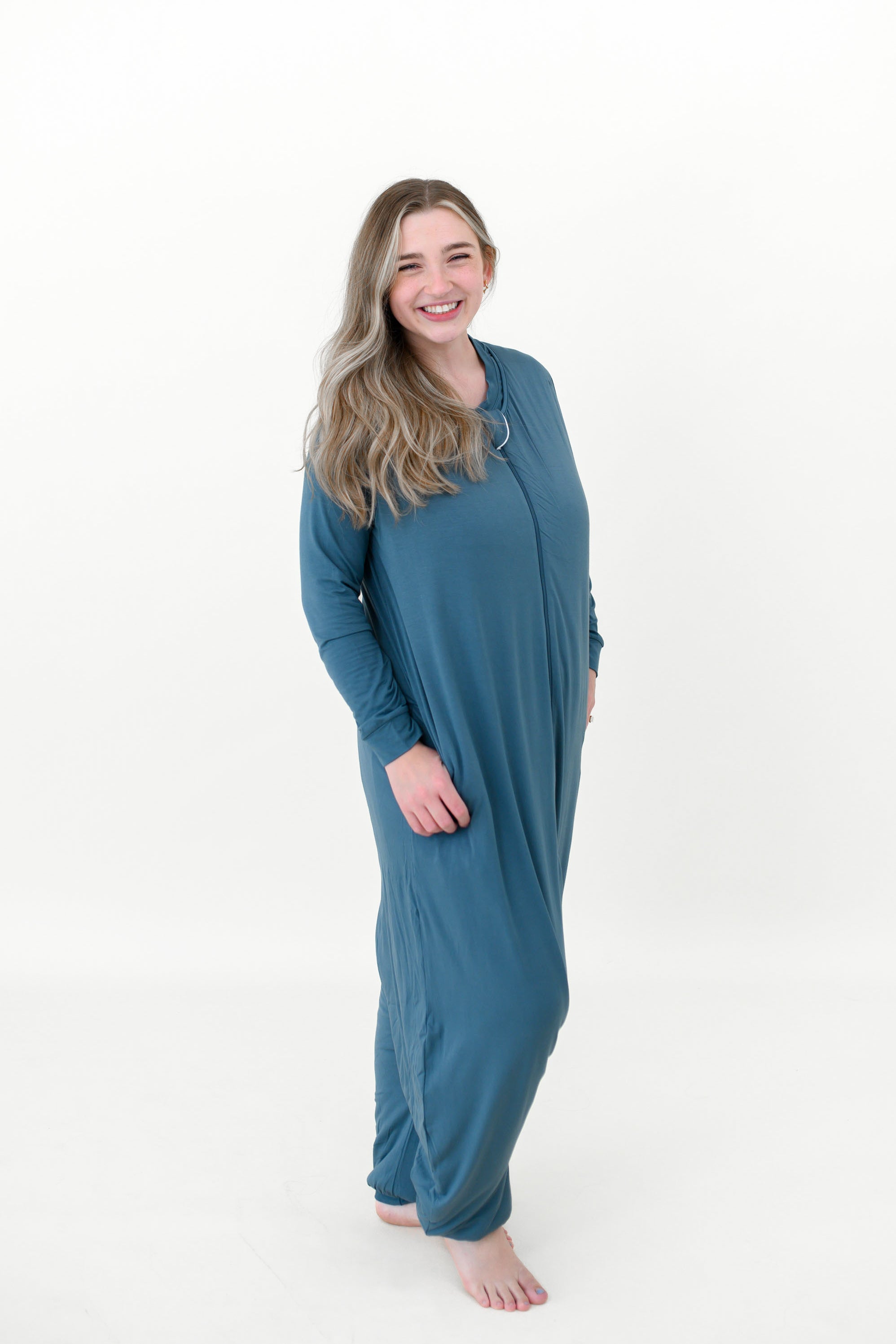 Model standing in a white room while wearing a Kyte Baby Adult Sleep Bag Walker in Adult