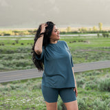Model in a grassy field looking away with her hand in her hair while wearing Women's Biker Short Set in Atlantic 