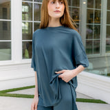 Woman wearing a teal outfit standing in front of a glass door. ::: Model is 5'6" wearing size S ///