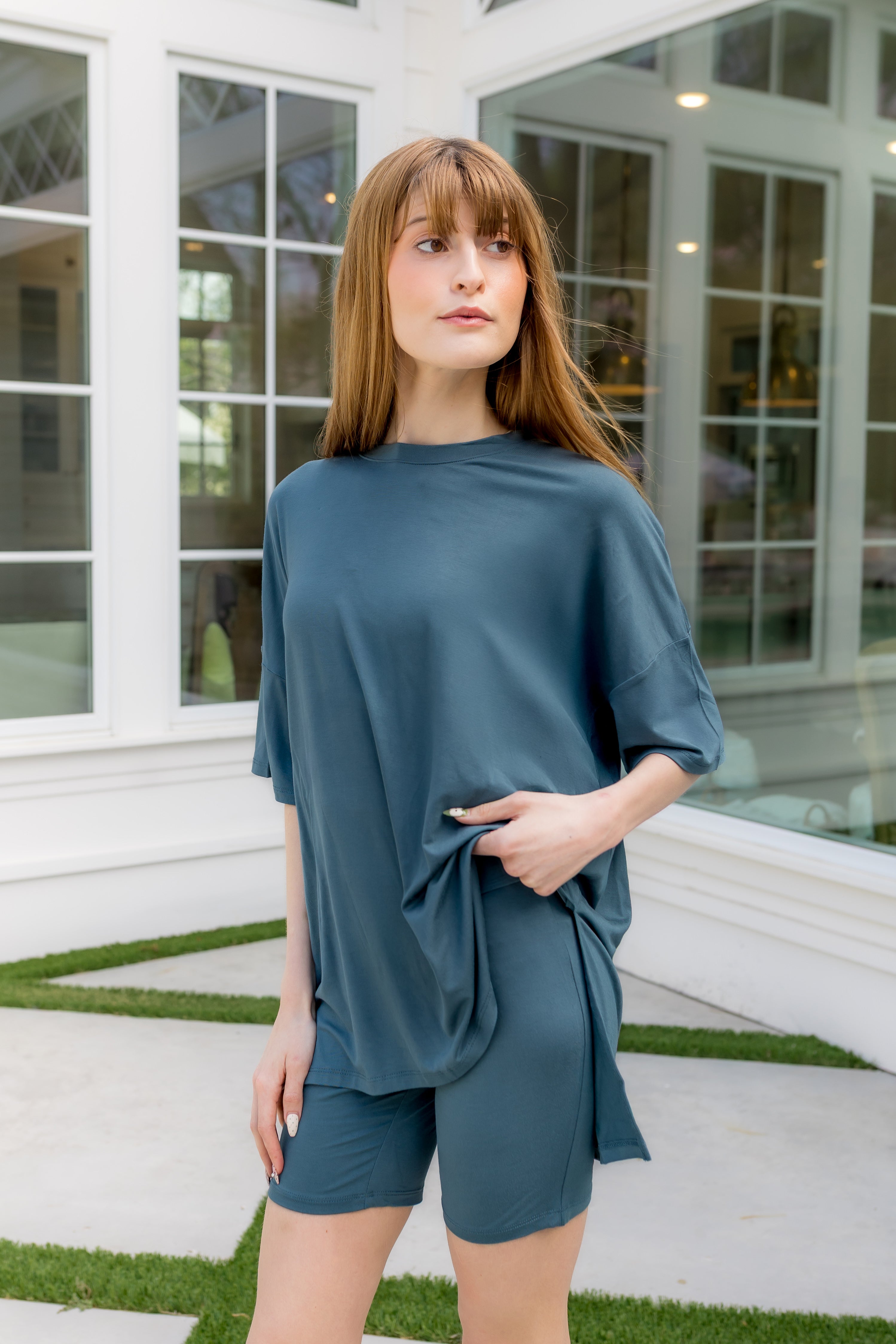 Woman wearing a teal outfit standing in front of a glass door.