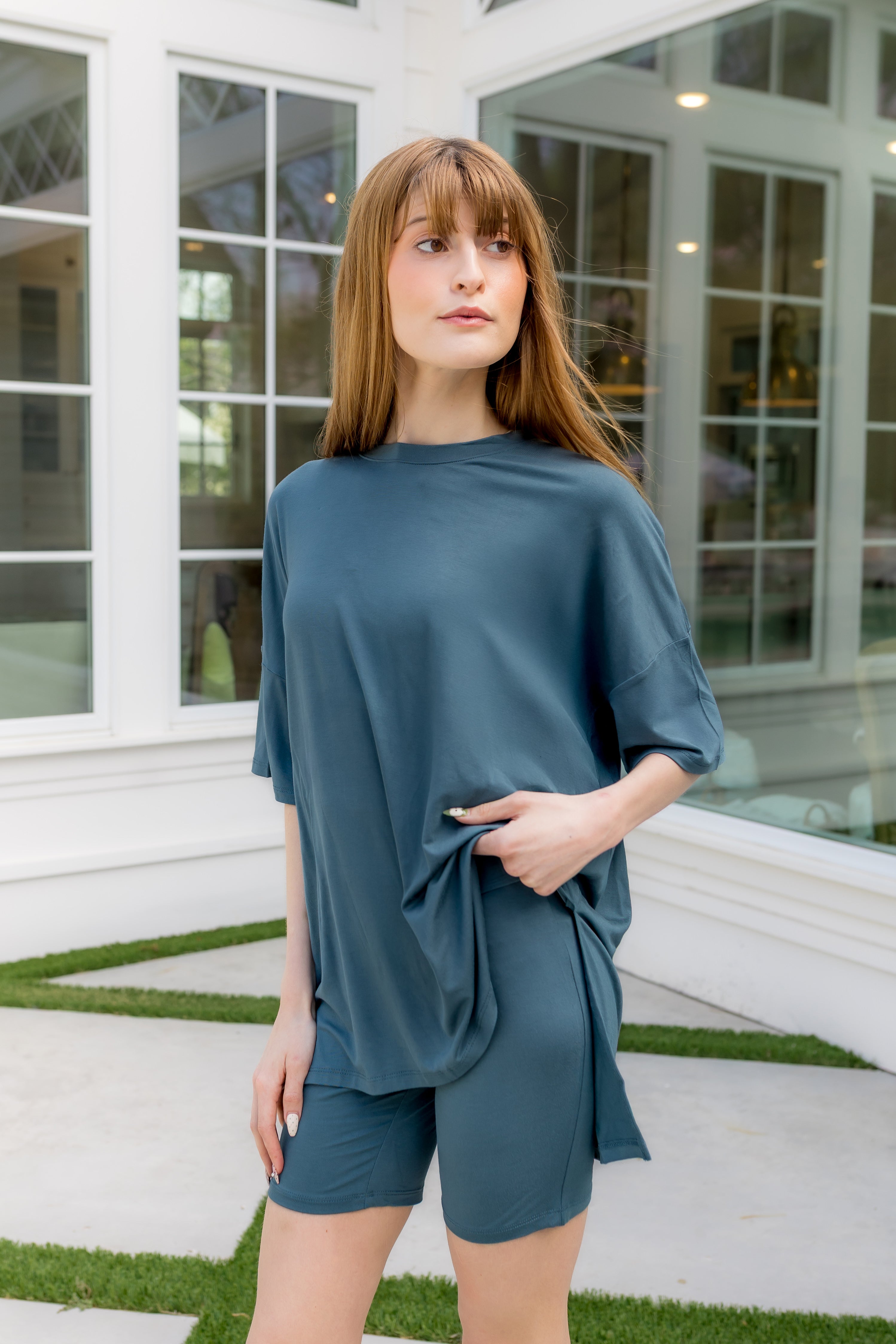 Woman wearing a teal outfit standing in front of a glass door. 