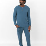 Male model standing looking off to the side with one hand in the pants pocket of the Men's Ribbed Henley Set in Atlantic in front of a white background