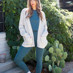 Model wearing the Bamboo Flex Women’s Leggings in Atlantic with matching short sleeve tee with an oat Chunky Knit oversized cardigan overtop