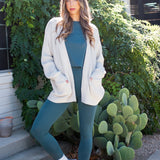 Model wearing the Bamboo Flex Women’s Leggings in Atlantic with matching short sleeve tee with an oat Chunky Knit oversized cardigan overtop
